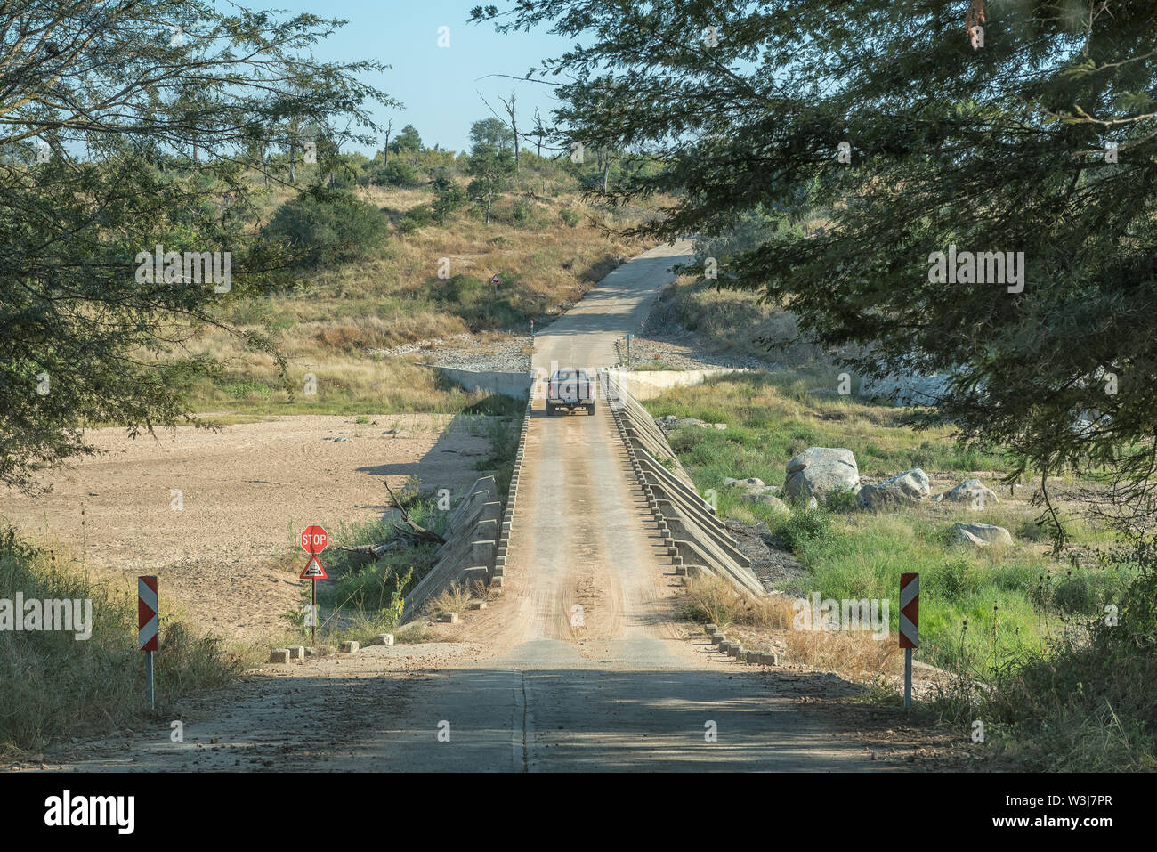 Krüger National Park, Südafrika - Mai 4, 2019: einspurige Brücke der niedrigen Wasser auf Straße S25 über die bume River. Ein Fahrzeug ist der Überquerung des Flusses Stockfoto