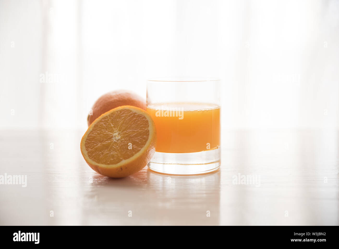 Orangen mit einem Glas Orangensaft auf weißem Hintergrund Stockfoto