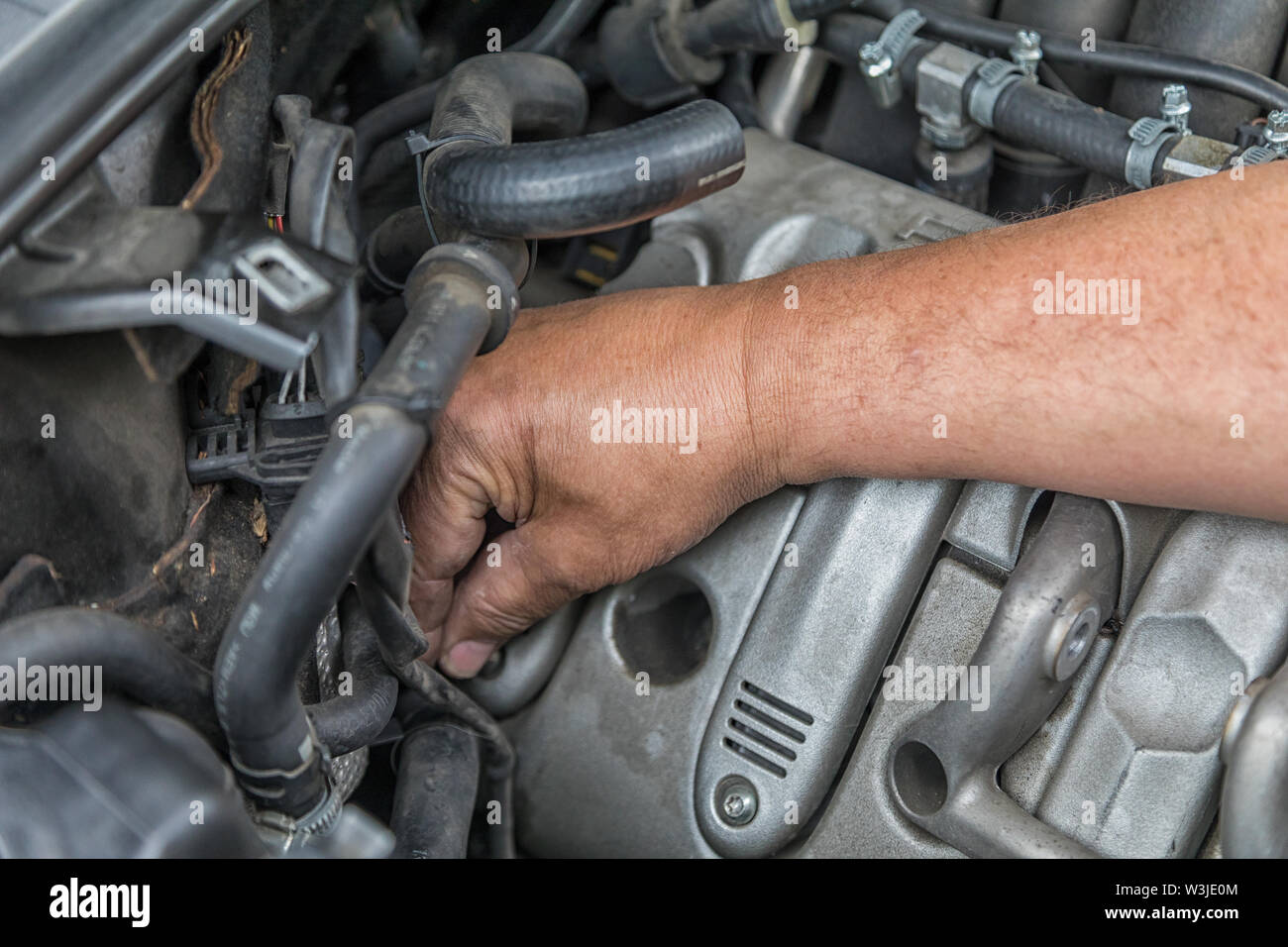 Eine Hand Reparaturen im Motorraum eines Autos. Stockfoto