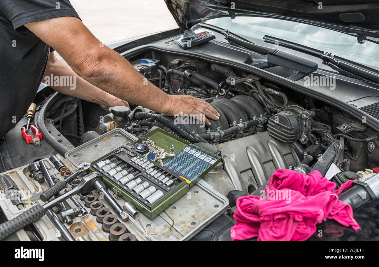 Zwei Hände Reparaturen im Motorraum eines Autos. Stockfoto