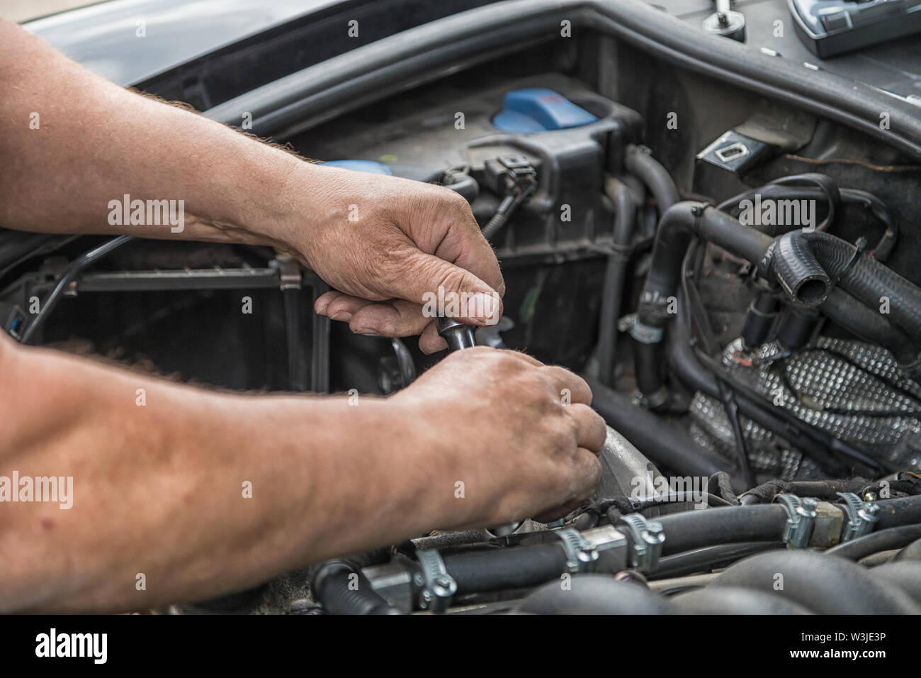 Zwei Hände Reparaturen im Motorraum eines Autos. Stockfoto