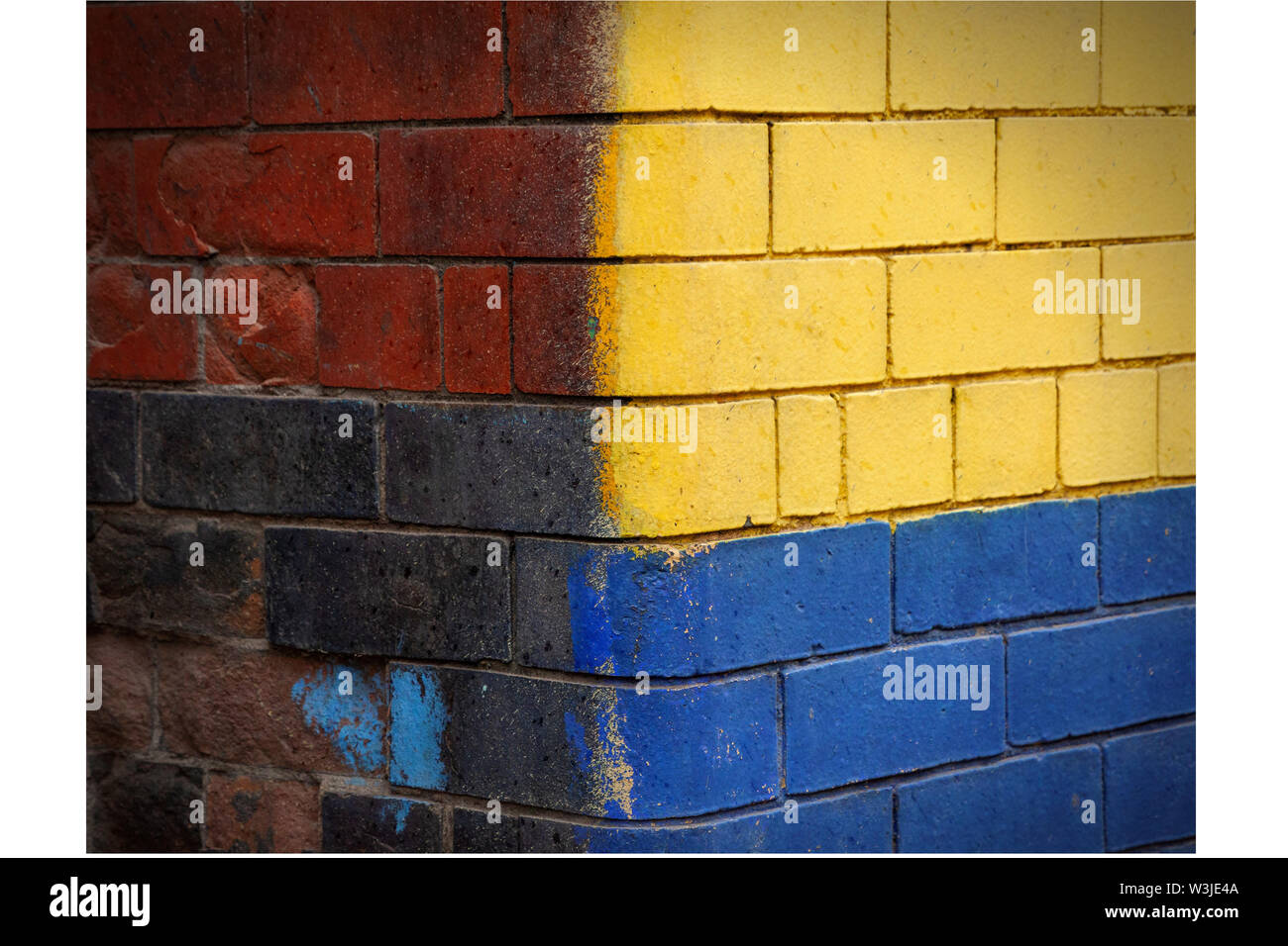 Hell lackierte gelbe und blaue Zementblockwand im Norden Vereinigtes Königreich Stockfoto