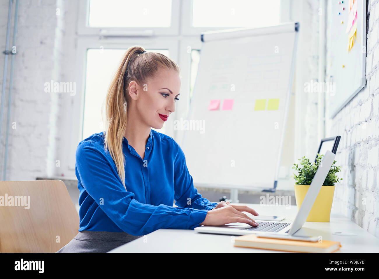 Attraktive Frau Arbeiten am Laptop in Start-up-Büro Stockfoto
