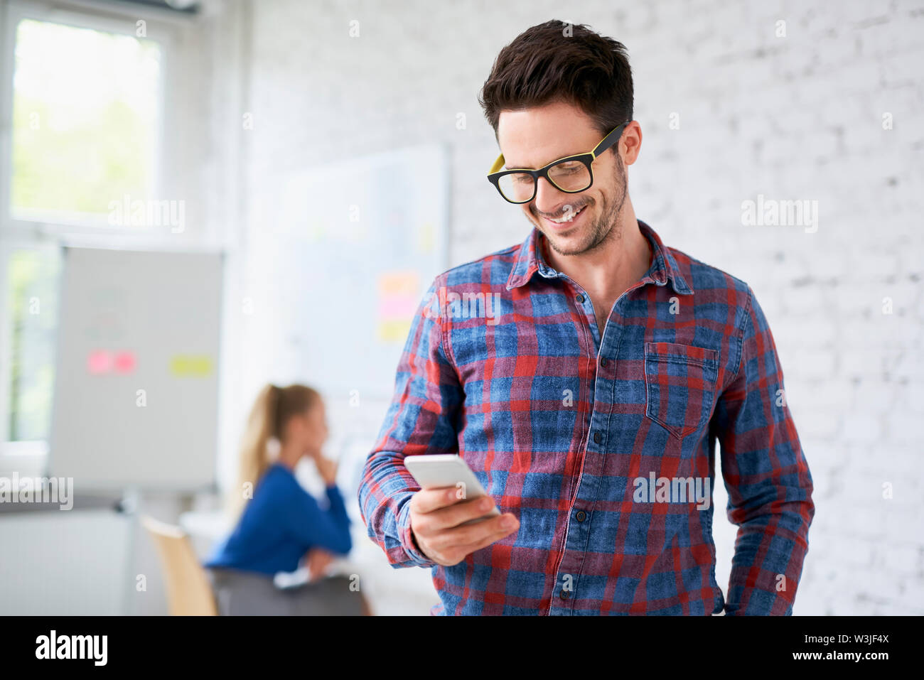 Happy Hipster mit seinem Telefon in Start-up-Büro Stockfoto