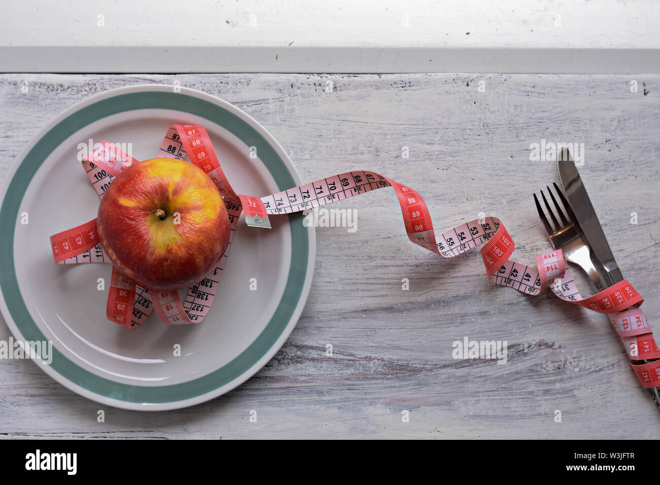 Apple auf Teller mit Maßband, Messer und Gabel. Ernährung Lebensmittel auf hölzernen Tisch. Gewichtskontrolle - Bild Stockfoto