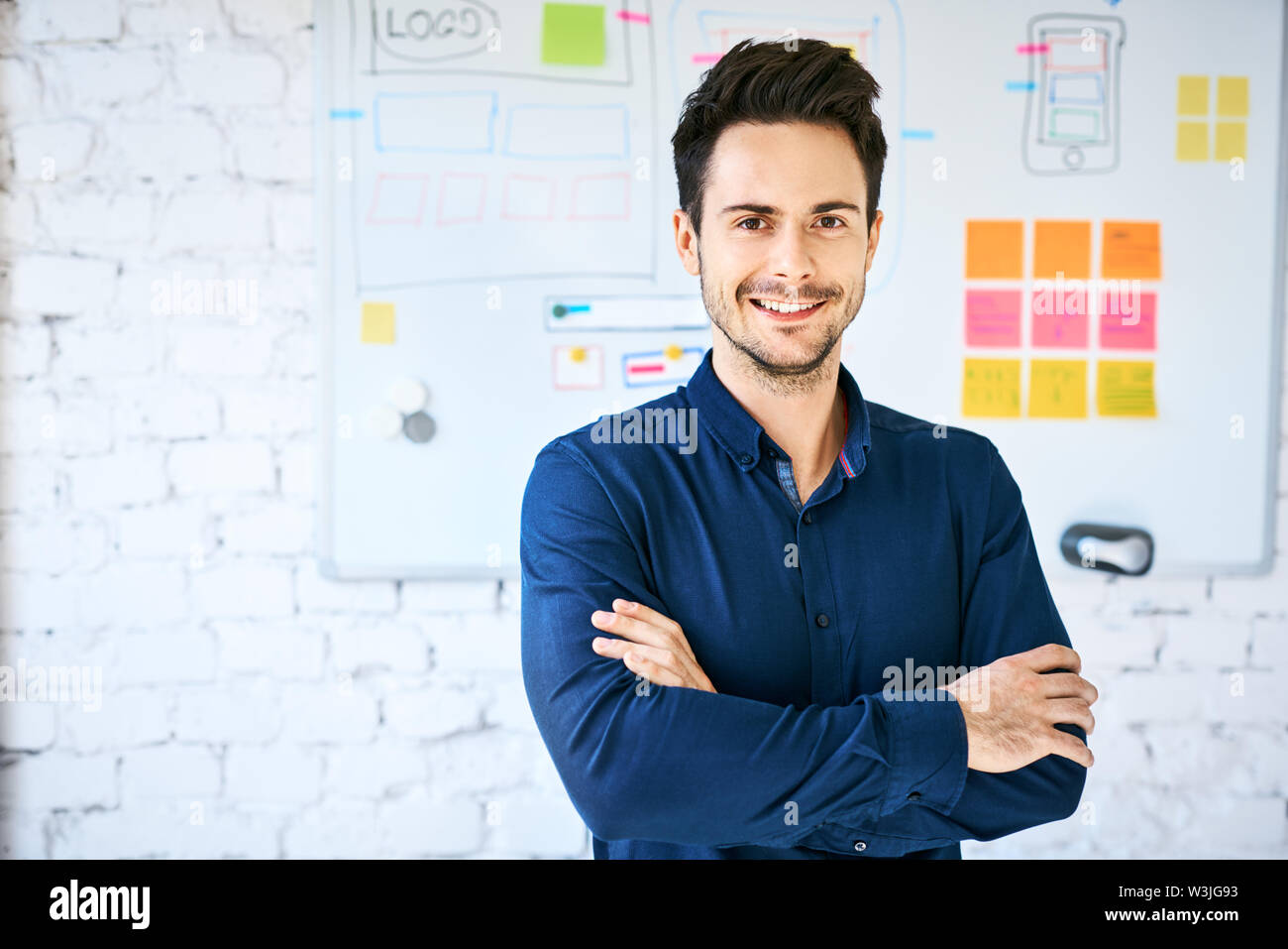 Zuversichtlich Web Designer im Büro auf Kamera, stand vor der Wand mit Whiteboard mit Website Drahtmodell Stockfoto