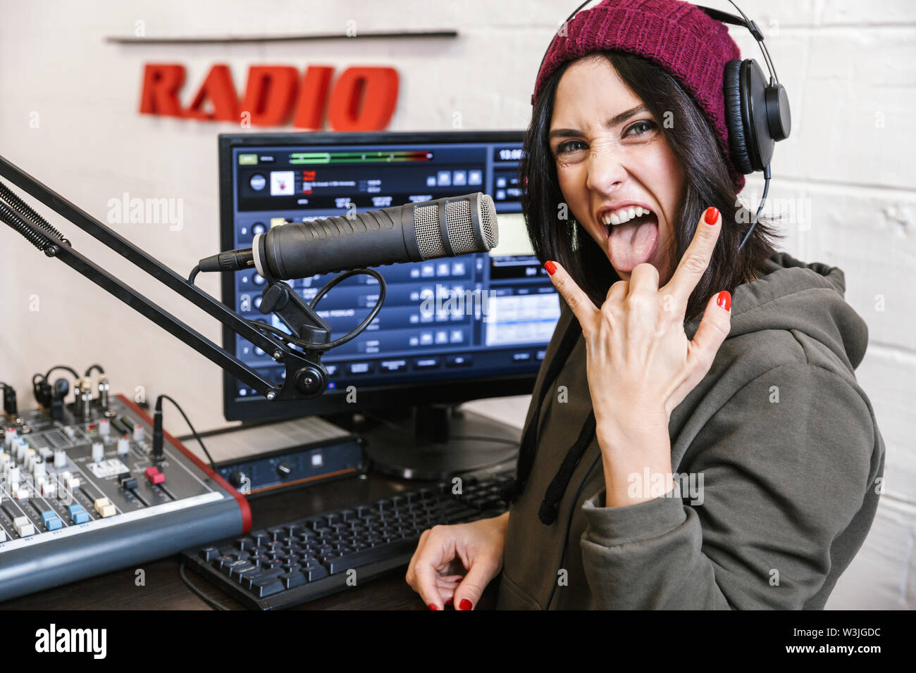 Fröhliche junge Frau radio Host Broadcasting über Mikrofon in Studio, Hörner Stockfoto