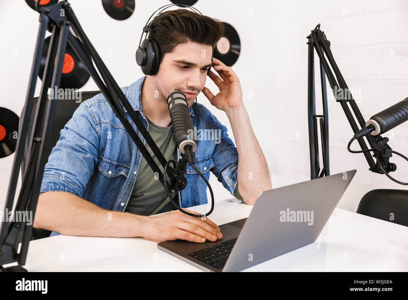 Glückliche junge Mann radio Host Broadcasting über Mikrofon in Studio, mit Laptop Stockfoto