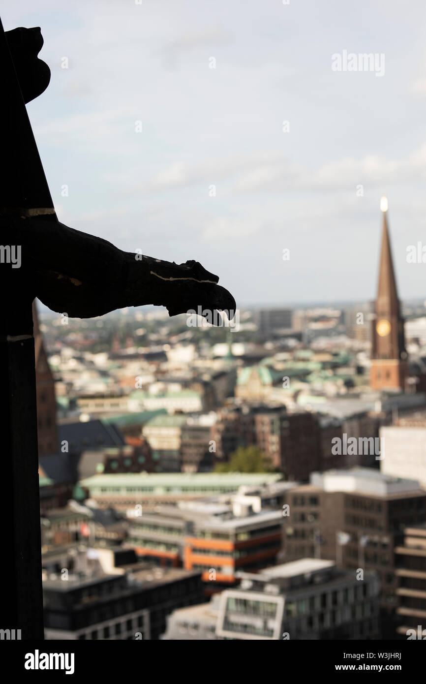 Eine Wasserspeier im Turm der St. Nikolauskirche in Hamburg mit Blick auf die Stadt. Stockfoto