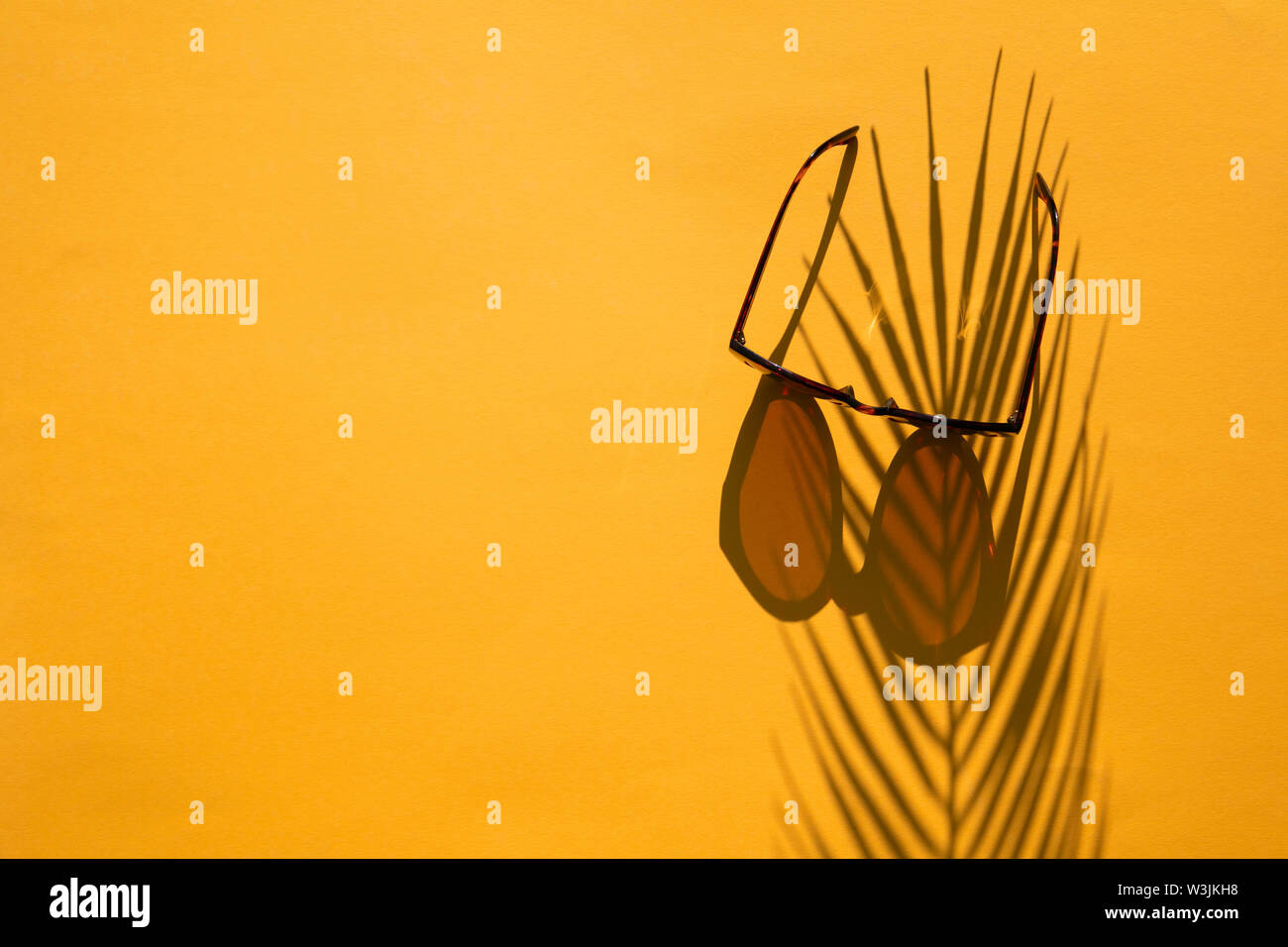 Sommer Hintergrund. Sonnenbrille mit einem palm leaf shadwo auf leuchtend gelb Stockfoto