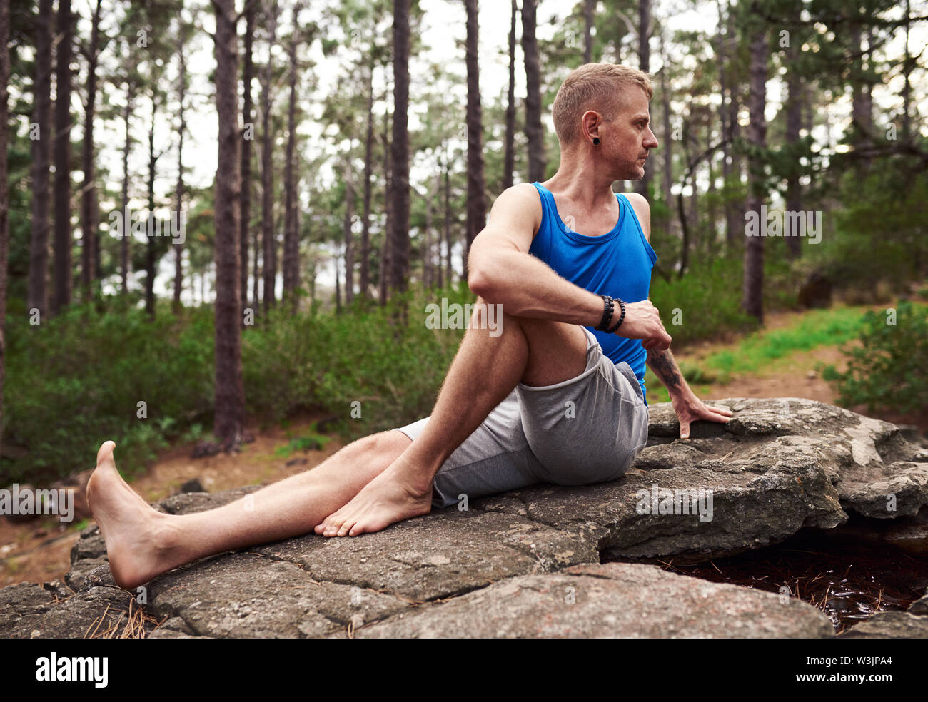 Mann, der sitzende Wirbelsäule verdrehen Pose in einem Wald Stockfoto