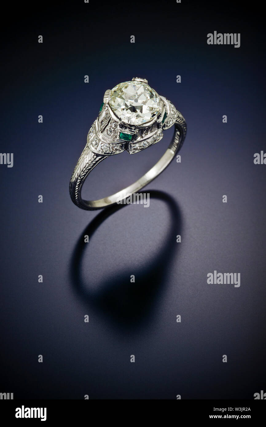 Diese antike Diamond Engagement Ring mit einem Plus carat Zentrum Stein und die von Akzent Seite Diamanten und emearld umgeben ist in graviert Platin eingestellt Stockfoto