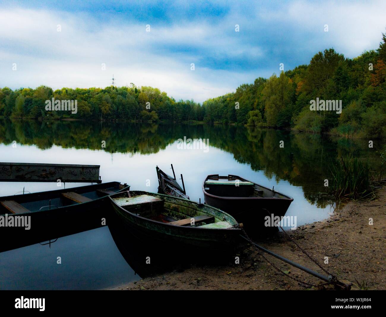 Boote auf spiegelnden Meer Wasser mit Bäumen im Hintergrund und bewölkter Himmel Stockfoto