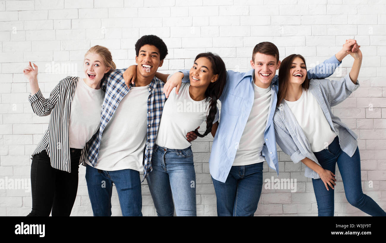 Diverse Teens umarmen und über weiße Mauer posing Stockfoto