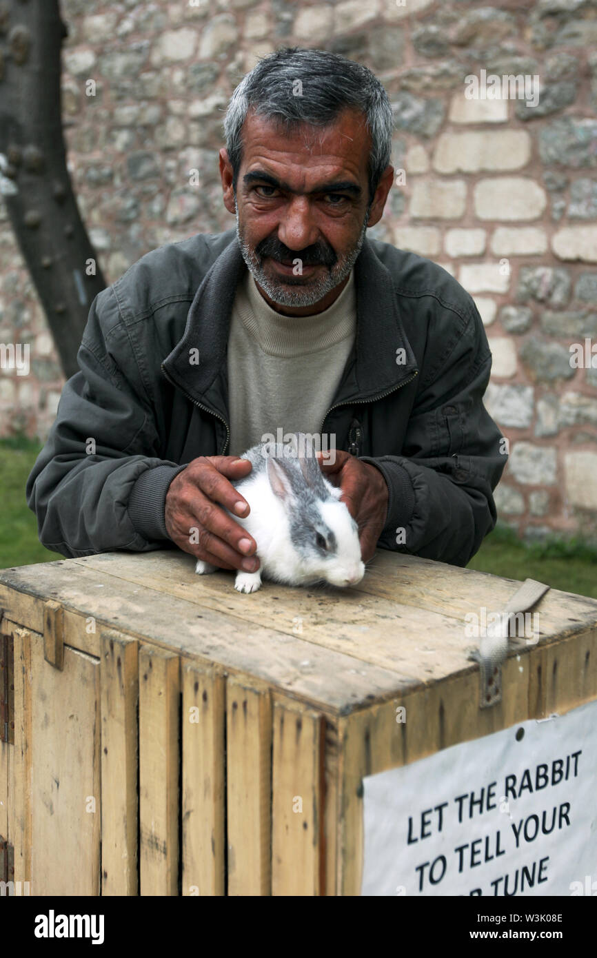 Ein türkischer Mann mit seinem Wahrsagen Hasen, der Touristen im Stadtteil Sultanahmet in Istanbul in der Türkei amüsiert. Stockfoto