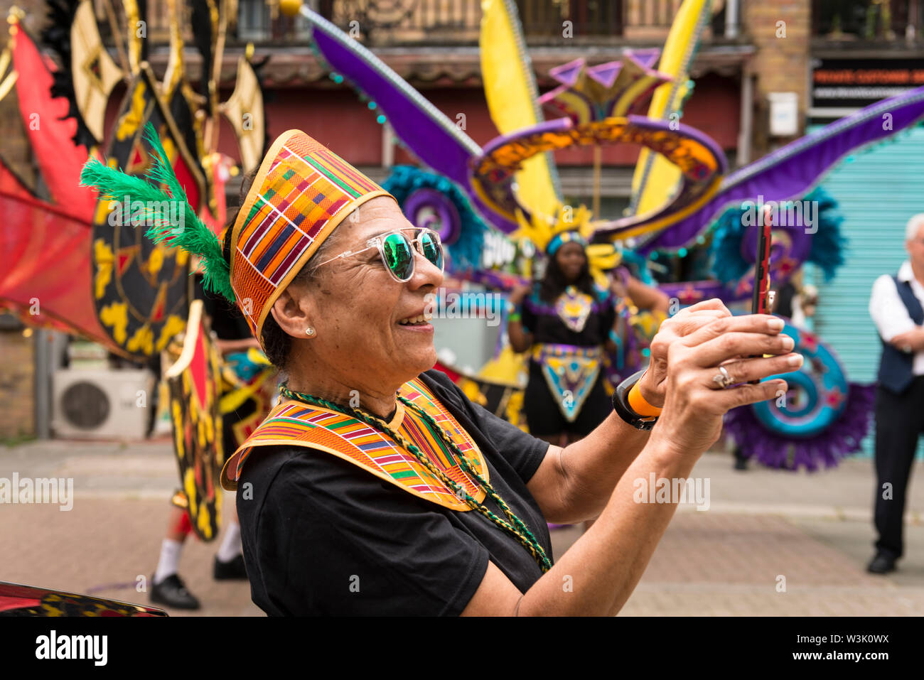 Ein Darsteller die Fotos vor dem Start der Acton Carnival Parade, 2019. Der Crown Street, Acton London UK Stockfoto