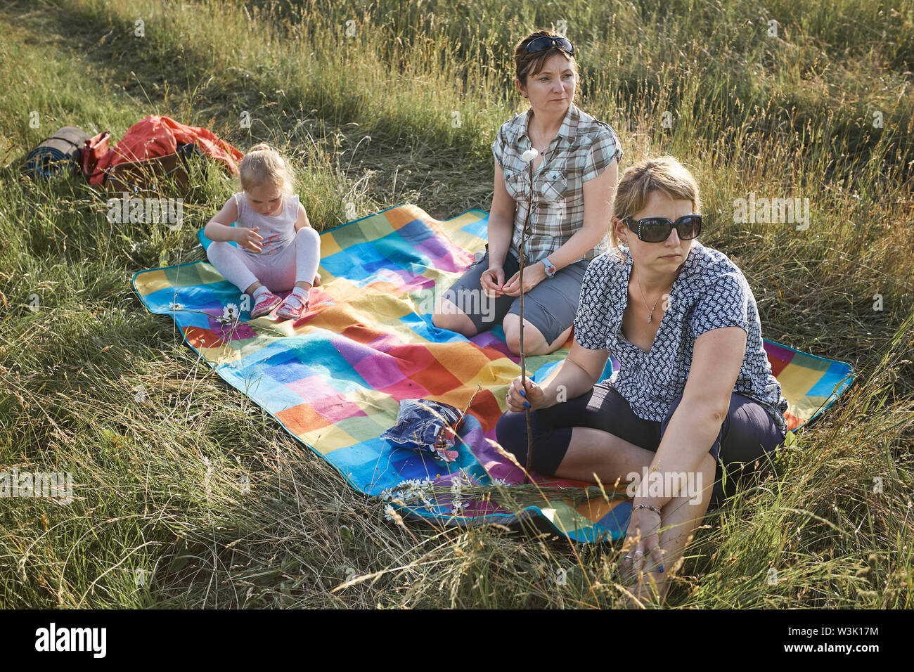 Familie Ausgabe Zeit zusammen auf einer Wiese, in der Nähe der Natur, Braten, Marshmallows über einem Lagerfeuer, Eltern und Kinder zusammen spielen und Sitzen o Stockfoto