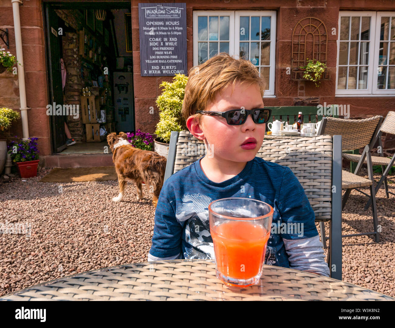 Tyninghame Schmiede Teestube, tyninghame Dorf, East Lothian, Schottland, Vereinigtes Königreich, 16. Juli 2019. UK Wetter: Sonnenschein am Café im Freien. Jamie, 8 Jahre alt, genießt ein kaltes Getränk mit Kohlensäure Stockfoto