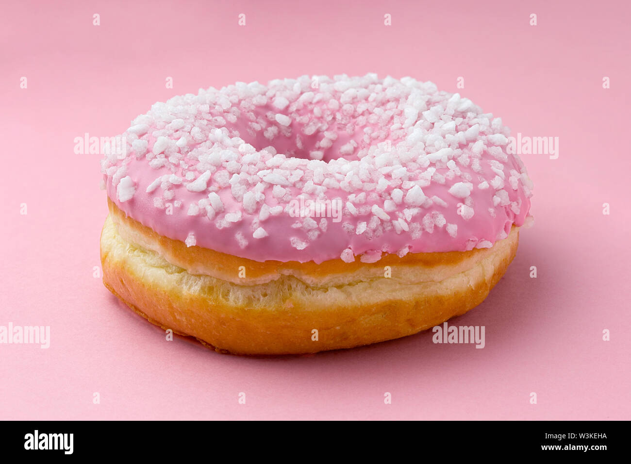 Rosa matt Donut mit Kristallzucker auf rosa Hintergrund isoliert bestreut. Stockfoto