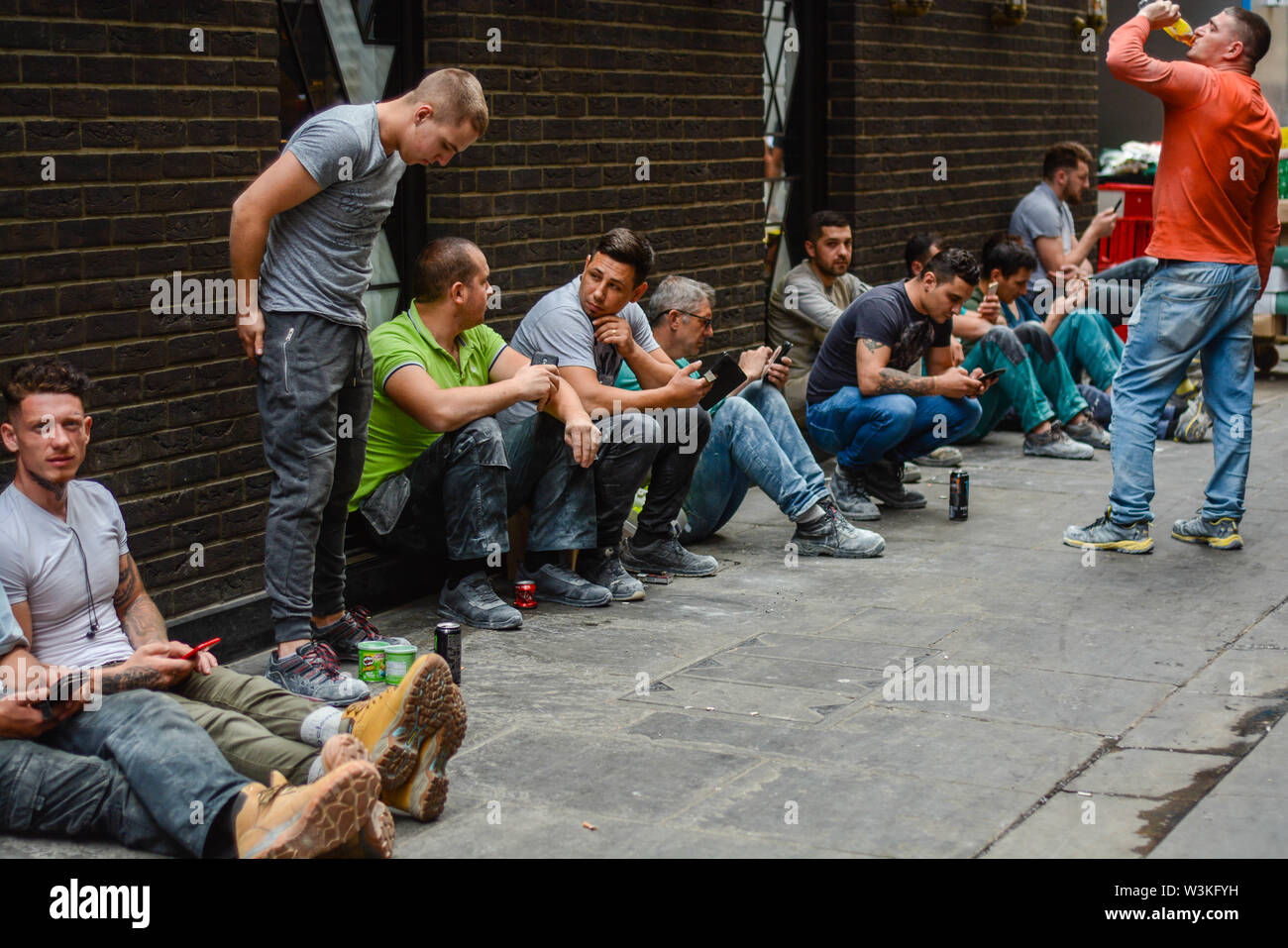 Bauarbeiter mit einer Unterbrechung beim Sitzen auf dem Boden Stockfoto
