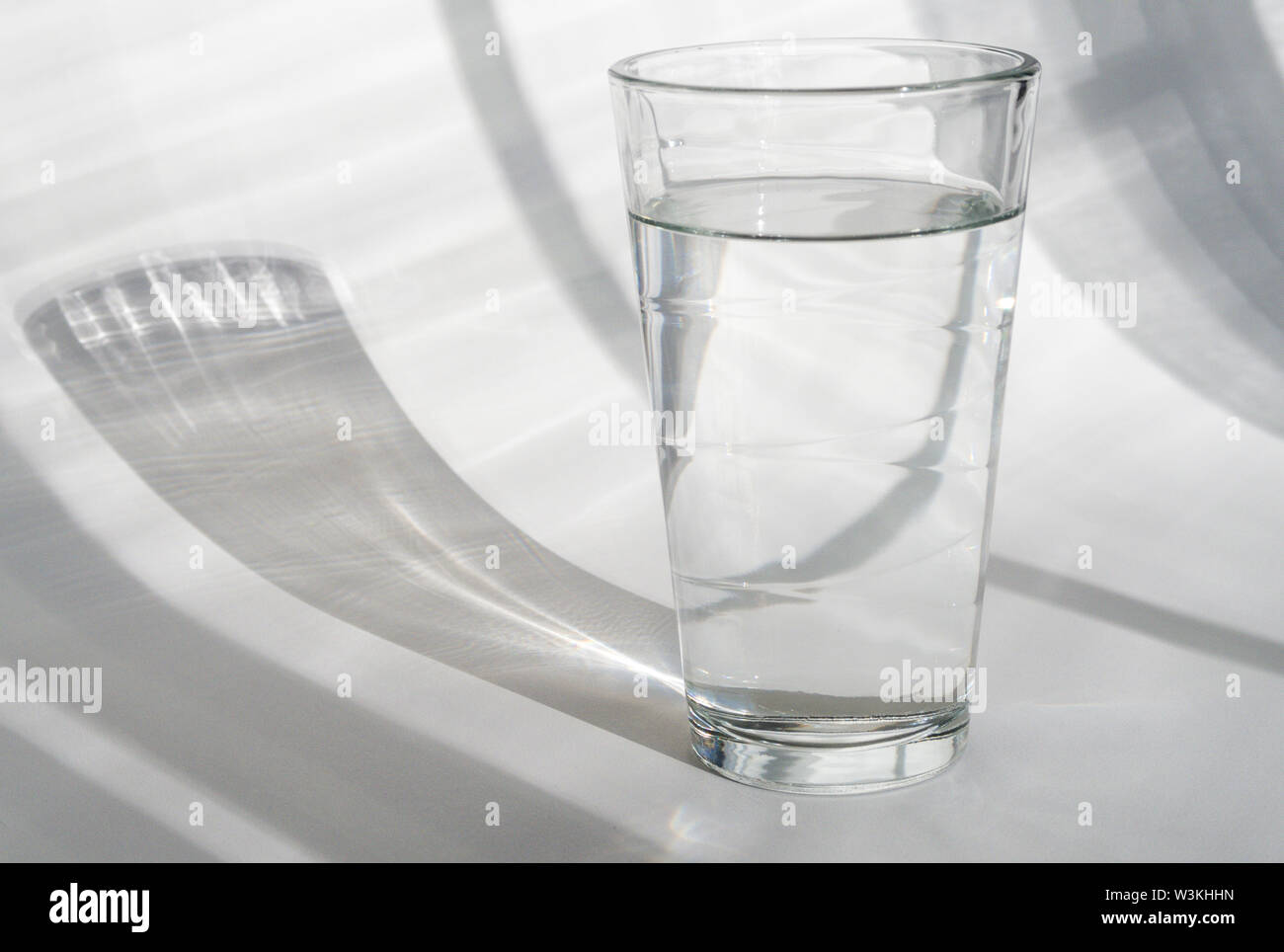 Glas Wasser auf weißem Hintergrund mit Schatten Stockfoto
