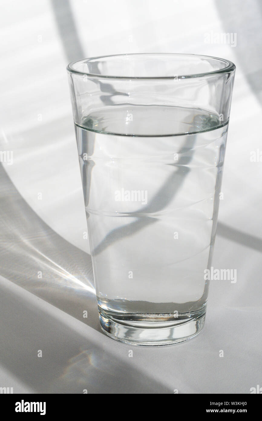 Glas Wasser auf weißem Hintergrund mit Schatten Stockfoto