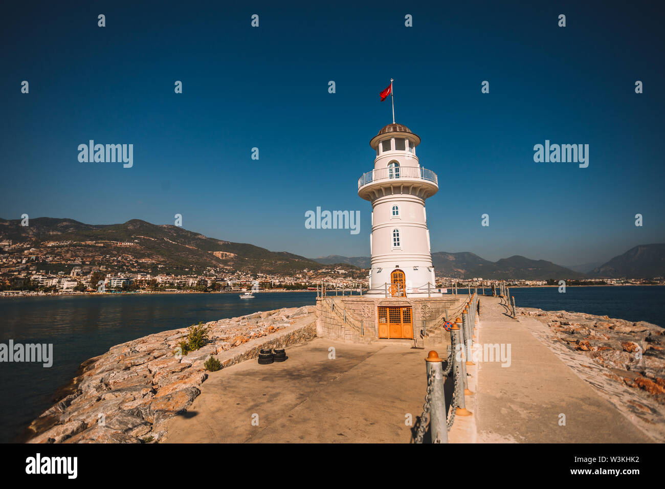 Schön und kleinen weißen Leuchtturm im Hafen von Alanya mit großen alten Schiff im Hintergrund, Türkei, Antalya, Bezirk Stockfoto