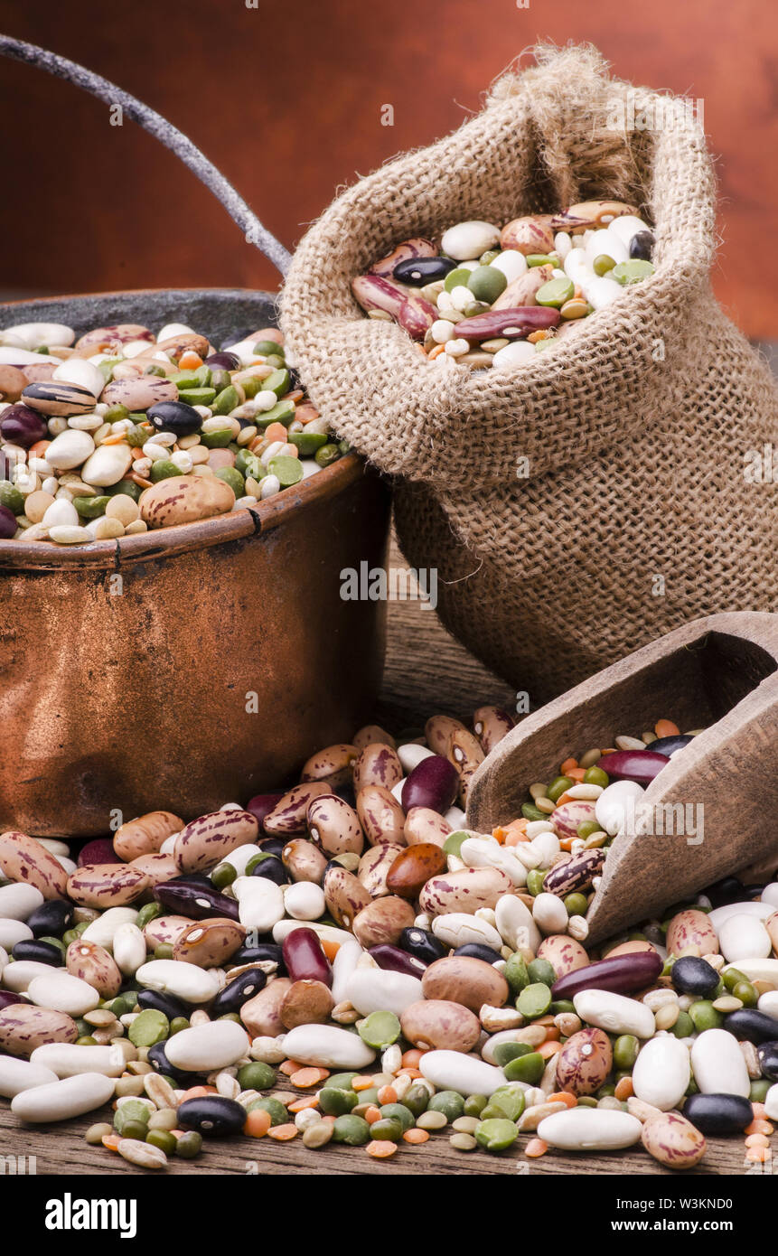 Hülsenfrüchte und getrocknete Getreide gemischt in einem Kupfer Topf und eine Tüte Yuta auf rustikalen Holztisch. Still Life Stockfoto