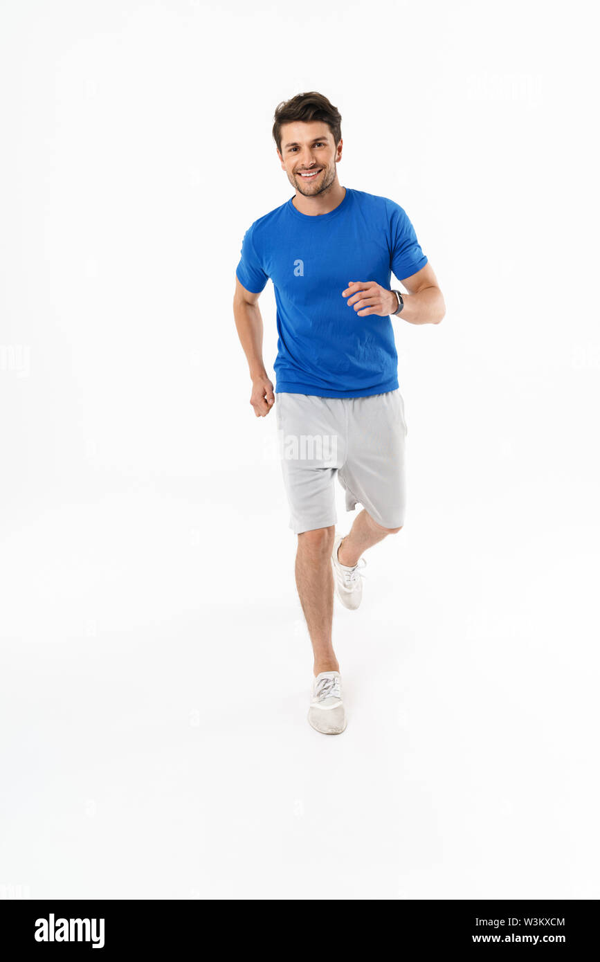 Foto der freudigen athletischen Mann in Shorts und T-Shirt lächelnd, während im Training läuft auf weißem Hintergrund Stockfoto