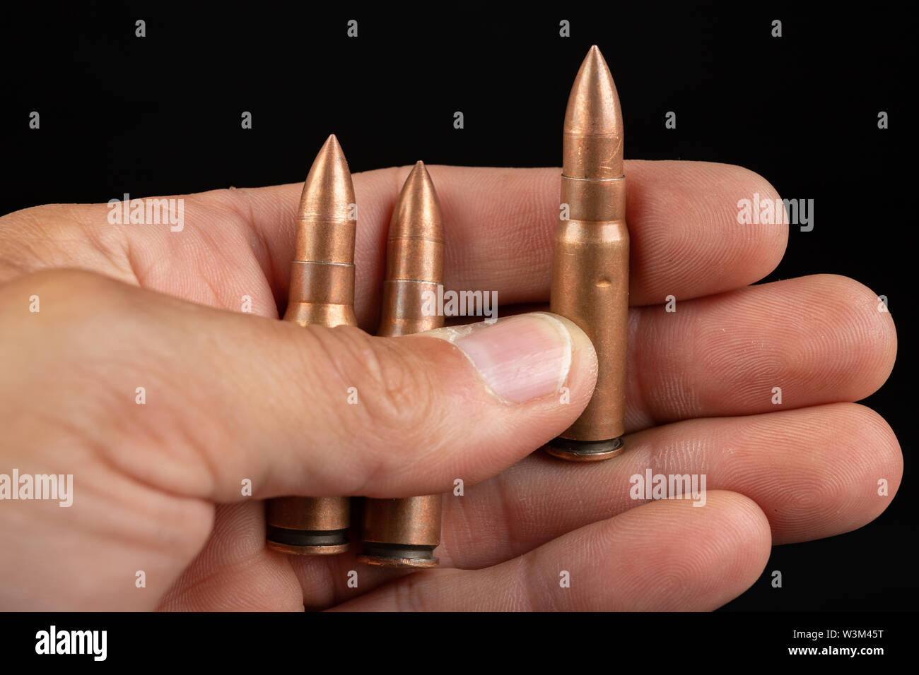 Munition für eine schnelle Gewehr in der Hand gehalten. Patronen für eine militärische Waffe. Der dunkle Hintergrund. Stockfoto