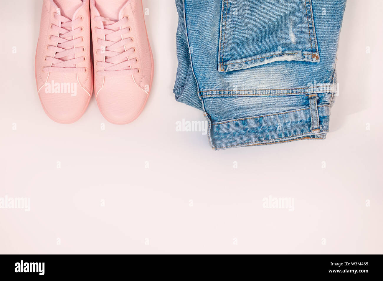 Flache Komposition mit einer Reihe von Kleidung, Jeans und rosa Turnschuhe. Ansicht von oben auf einem weißen Hintergrund. Flach, Ansicht von oben Stockfoto