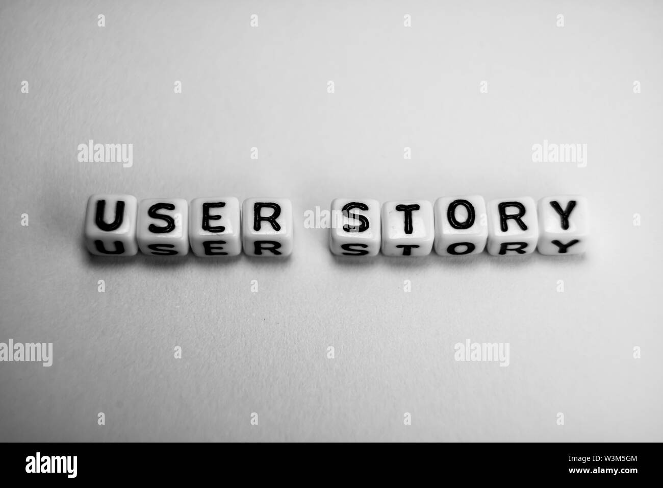 White Cubes mit Word USER STORY auf weißem Papier Hintergrund und dunkle Schatten Stockfoto