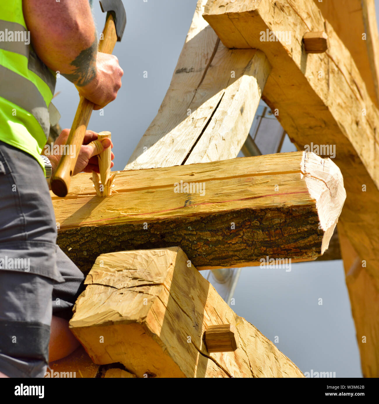 Tischler einfügen einen Keil in einem gemeinsamen Verriegelung peg in einem neuen traditionelle mittelalterliche Eiche Holz gerahmt Gebäude zu bauen Stockfoto