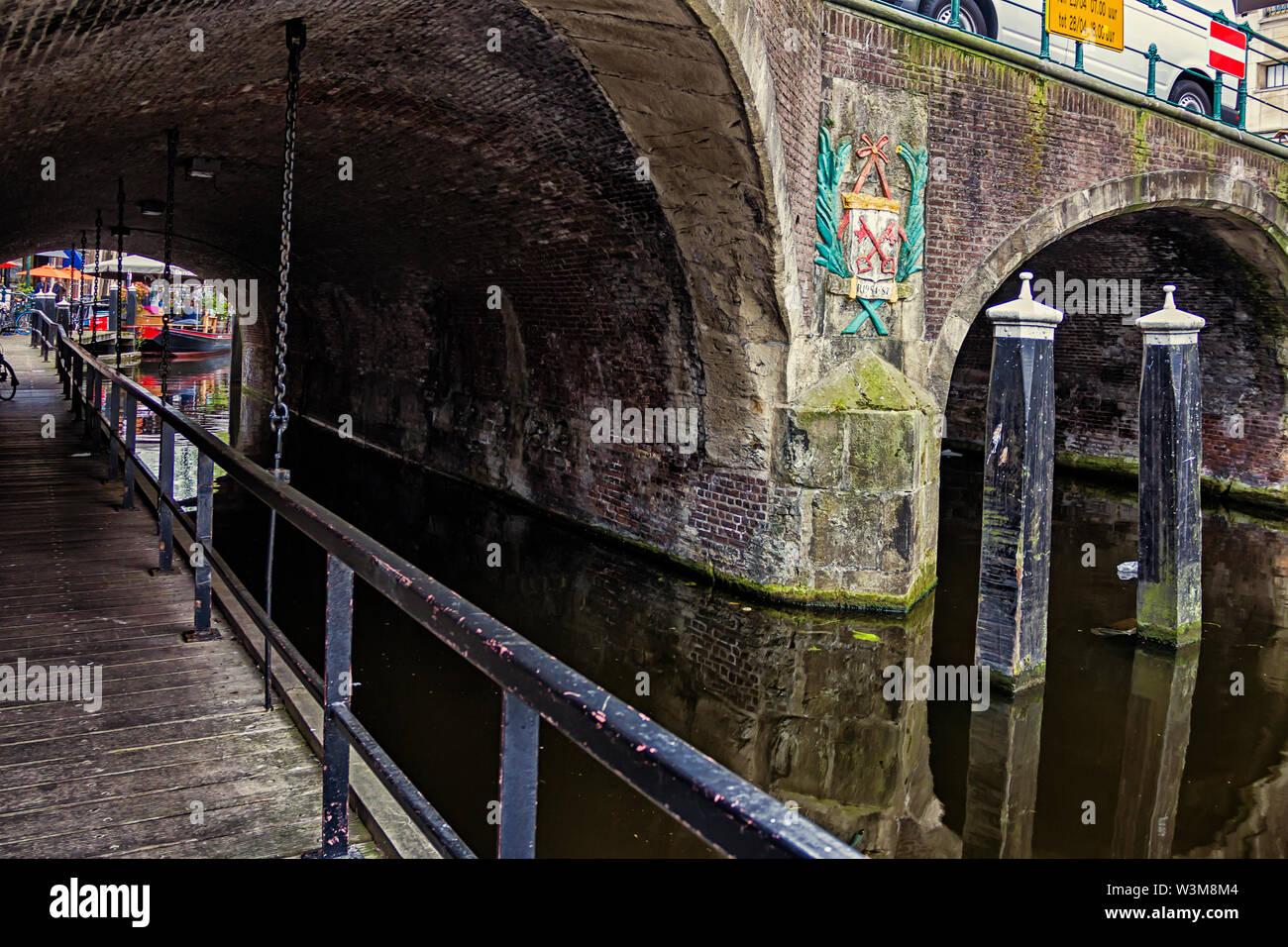 Leiden, Holland, Niederlande, April 18, 2019, Ansicht unter der Brücke Visbrug (Fisch), Säule mit dem Emblem von Leiden, Canal in Leiden Altstadt. Boote Stockfoto