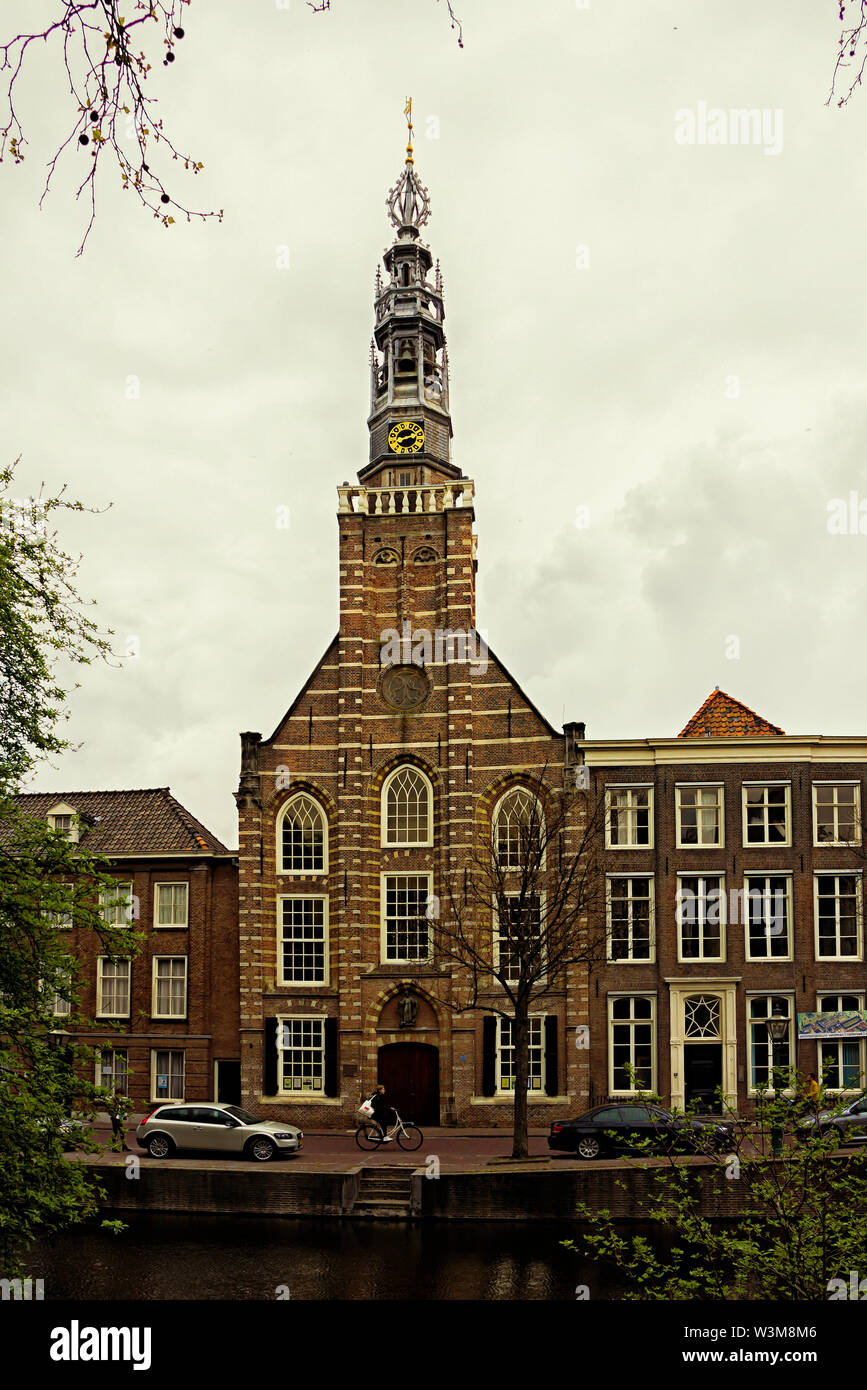 Leiden, Holland, Niederlande, April 18, 2019, St. Louis, Kirche (Heilige Lodewijkkerk) Fassade, front, Dame mit dem Fahrrad und Auto in der Nähe, Kanal in Lei geparkt Stockfoto