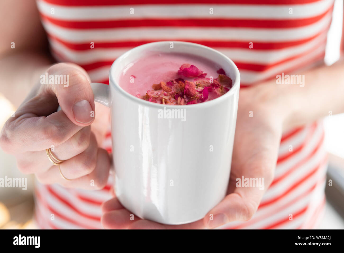 Frau mit rosa Trinken gekrönt mit Blütenblättern Stockfoto