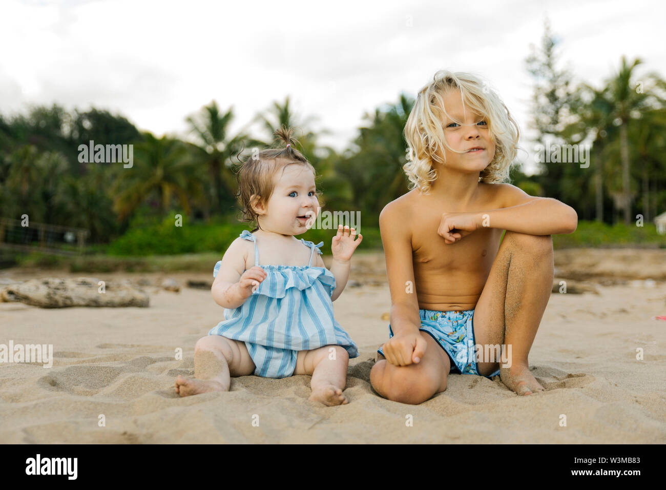 Jungen und seine kleine Schwester sitzen am Strand. Stockfoto