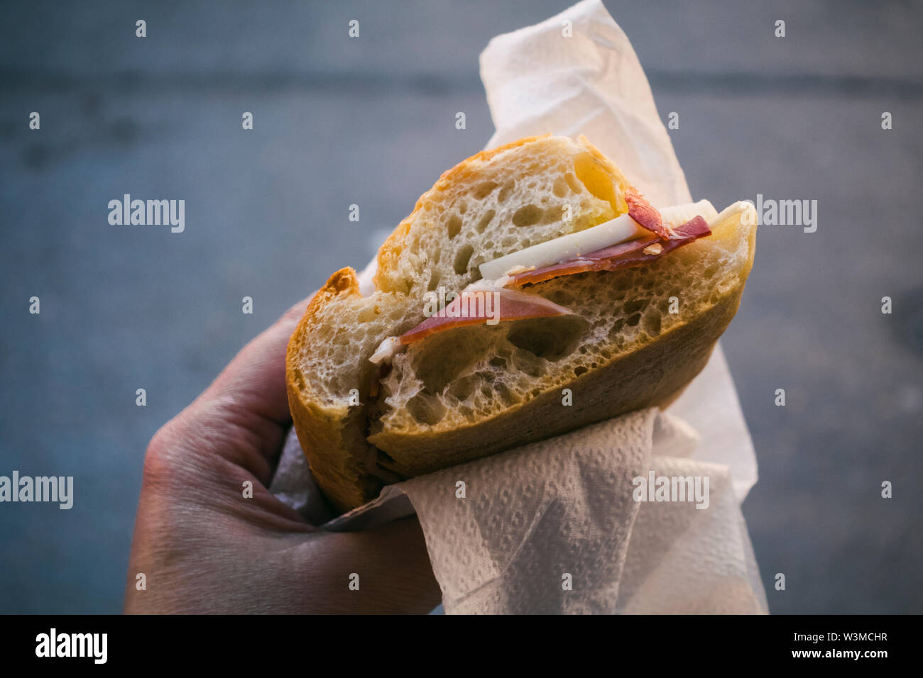 Woman's Hand mit Pancetta und Käse Sandwich Stockfoto
