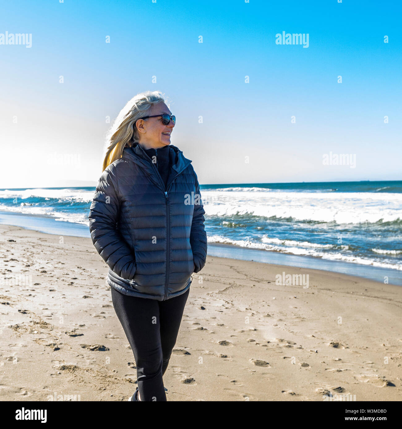 Reife Frau zu Fuß am Strand. Stockfoto