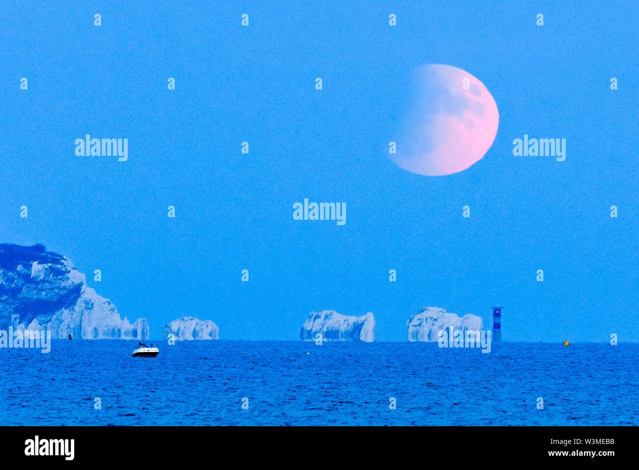 Die Nadeln, Isle of Wight, Großbritannien. 16. Juli 2019. UK Wetter. Die verdunkelte Vollmond erhebt sich über der Nadeln auf der Isle of Wight auf einem klaren ruhigen Abend. Heute Abend Mond in einer teilweise eclispe und ist auf maximal 60 Prozent werden durch die masseanschlüsse Schatten am 10:30 PM Uhr. Foto: Graham Jagd-/Alamy leben Nachrichten Stockfoto