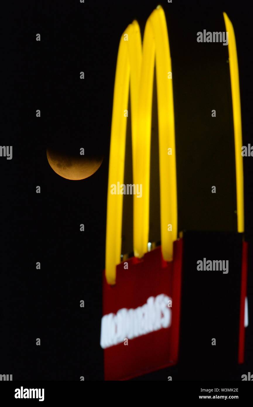 Glasgow, UK. 16. Jul 2019. Mond Mack. Es liebevoll von der McDonalds Drive Thru, die partielle Mondfinsternis von Wolken am Himmel in Glasgow gesehen. Credit: Colin Fisher/Alamy leben Nachrichten Stockfoto