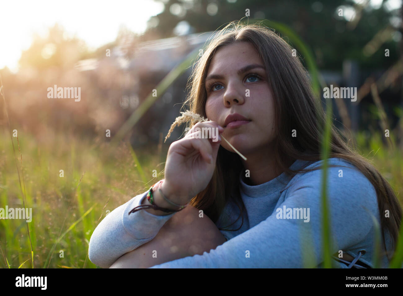 Teenage Mädchen im Gras sitzen im Sommer Landschaft. Stockfoto