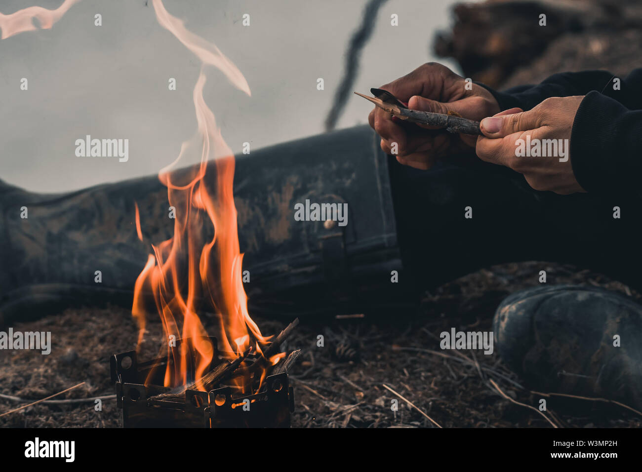 Frau Carving einen Stock über dem Lagerfeuer zu kochen. Yukon Territory, Kanada Stockfoto