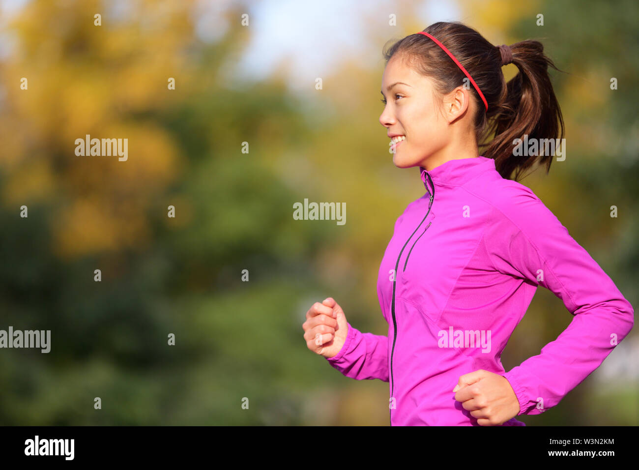 Asiatische Frau im Herbst Wald läuft im Herbst. Läuferin Training im Freien in warmem, fließendem Outfit. Schönen multi-ethnischen Chinesen Asiatische/Kaukasisch weiblich joggen. Stockfoto