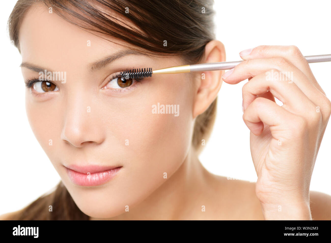 Wimperntusche woman putting Makeup auf die Augen. Asiatische Frau Modell Gesicht Nahaufnahme mit Auge Pinsel auf Wimpern. Stockfoto