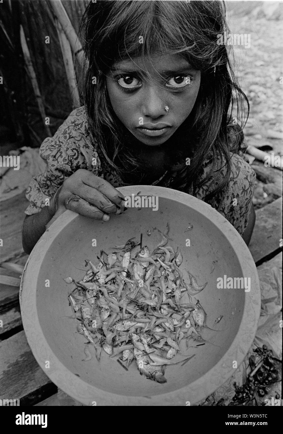 Ein junges Mädchen hält ein irdenes Gefäß, das einige Fische, dass das Abendessen für ihre Familie sein wird. Bau Basar Slum, auf der die Röcke von Dhaka. Bangladesch. Stockfoto