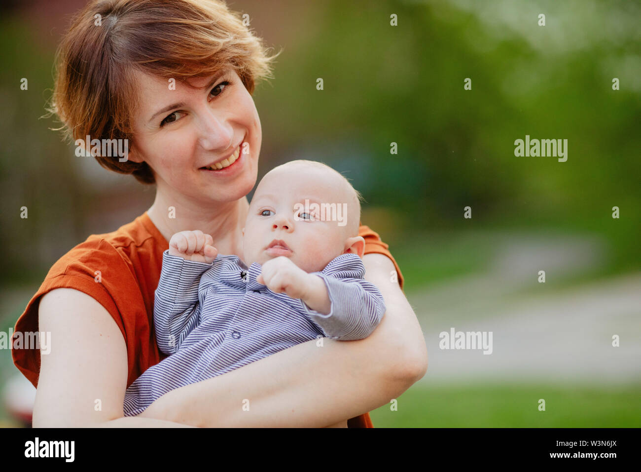 Fröhliche Mutter Holding Baby in den Armen Stockfoto