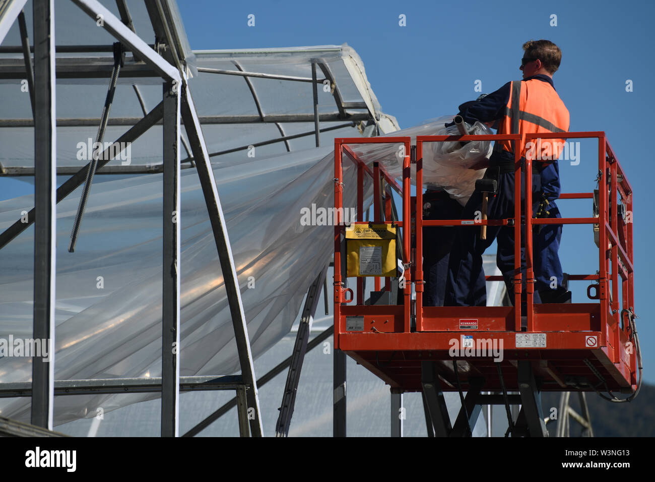 Greymouth, Neuseeland, 12. Dezember 2018: Handwerker sichern Sie den Kunststoff auf einen neuen Tunnel House. Stockfoto