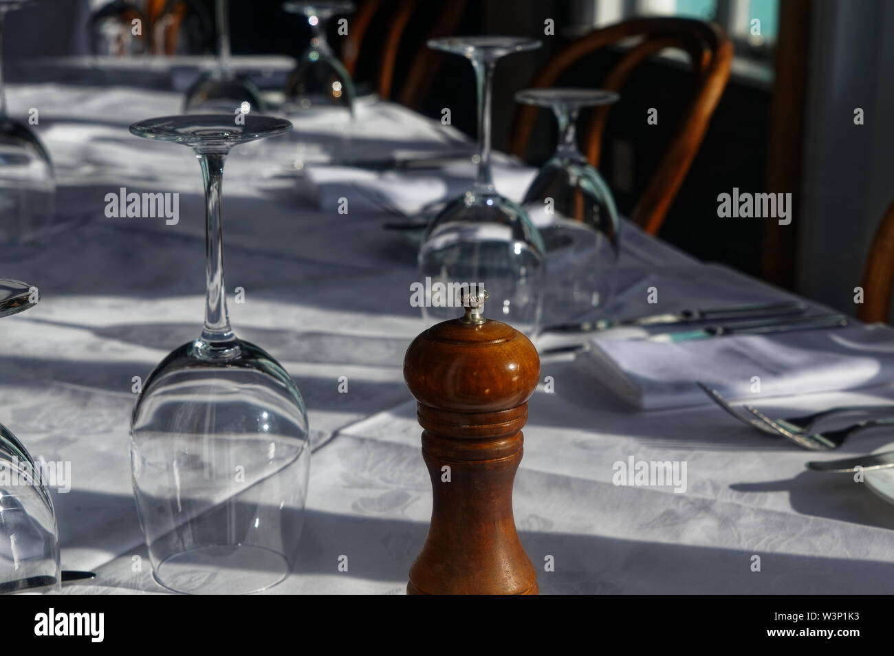 Eine hölzerne pepper Grinder ist an der Vorderseite einer Tabelle für eine formelle Mahlzeit eingestellt Stockfoto