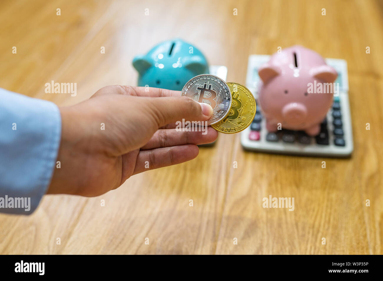 Frau Hand zwei BITCOINS vor sparschwein Stockfoto